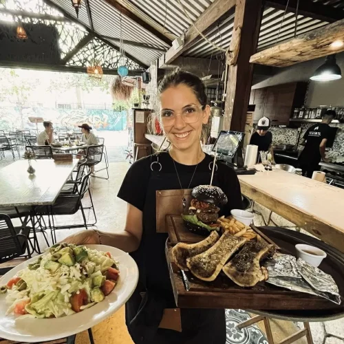Mesera mostrando platillos de un restaurante de carnes de Playa del Carmen