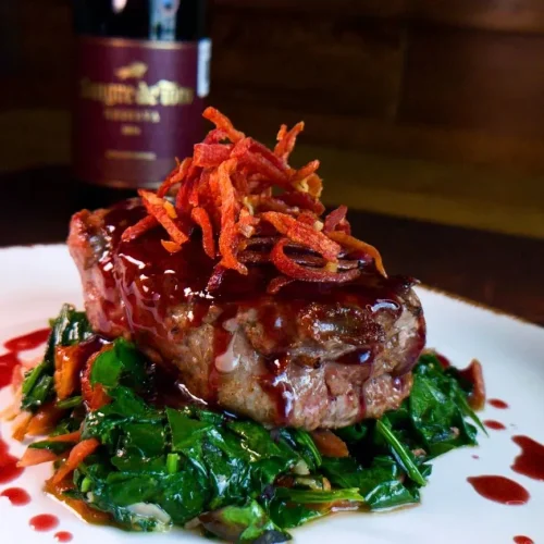 Plato con un filete de res al serrano y copa de vino en el lugar del bife pachuca