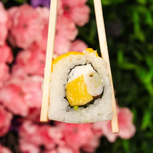 rollito de sushi agarrado con palillos chinos en natura rolls